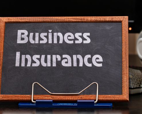 Business Insurance Services Concept. The text is written on a chalk board located at the workplace near the computer.