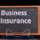 Business Insurance Services Concept. The text is written on a chalk board located at the workplace near the computer.