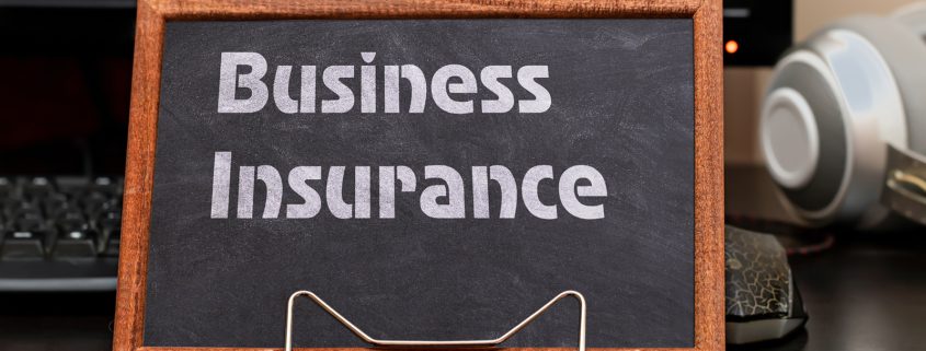 Business Insurance Services Concept. The text is written on a chalk board located at the workplace near the computer.